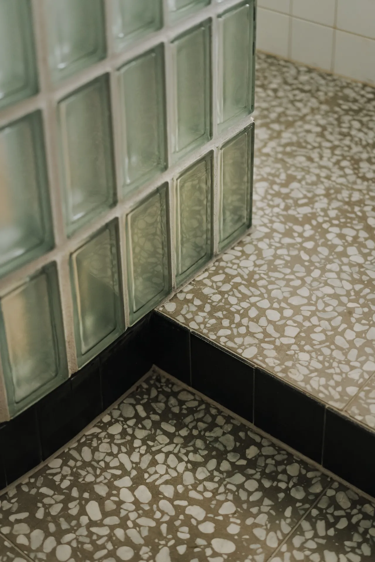Łazienka z miętowozielonymi kaflami strukturalnymi i terrazzo w beżu z białymi paciorkami, projektowanie wnętrz w stylu retro.